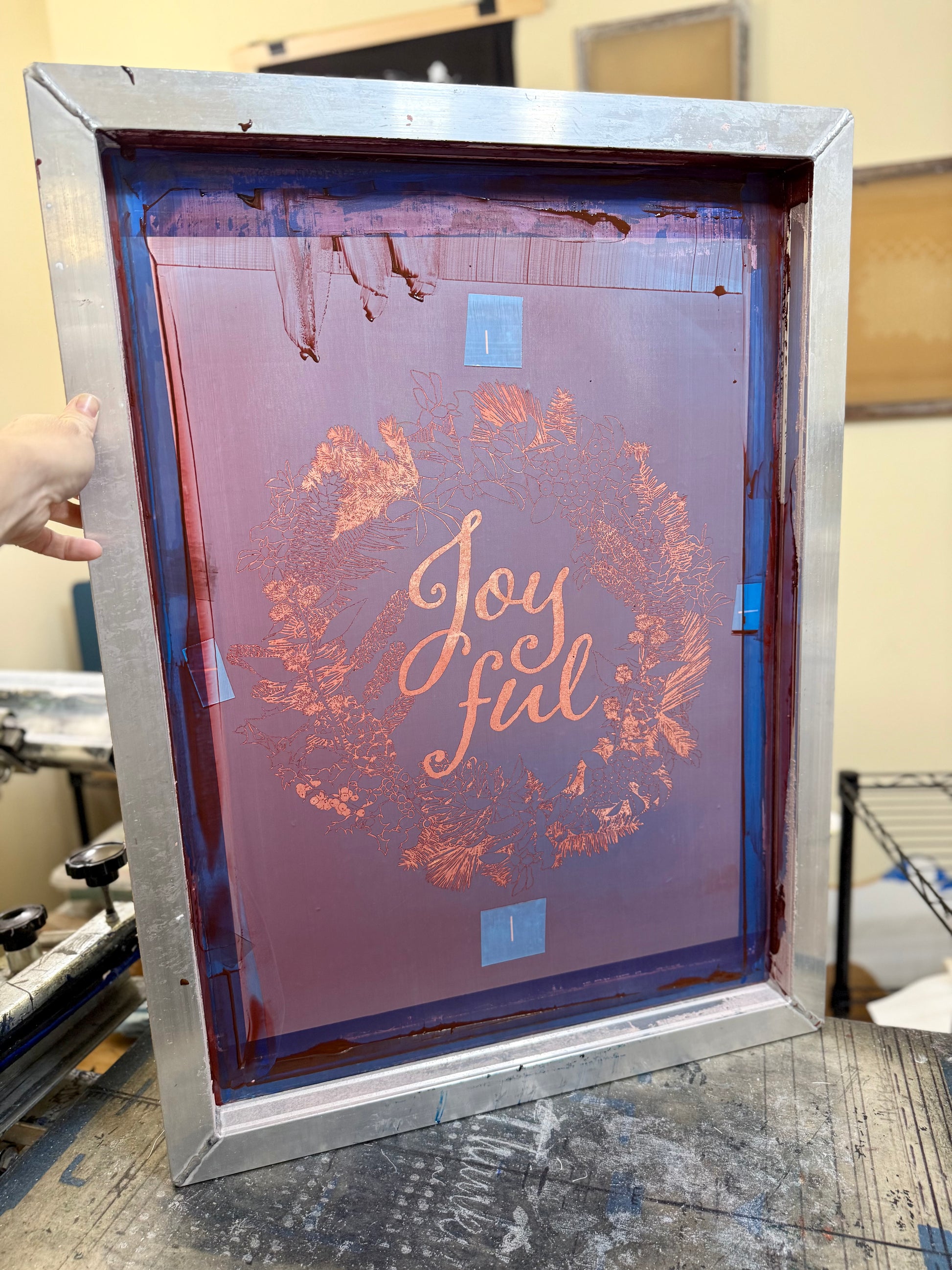 Hand-printed joyful holiday tea towel with festive botanical design