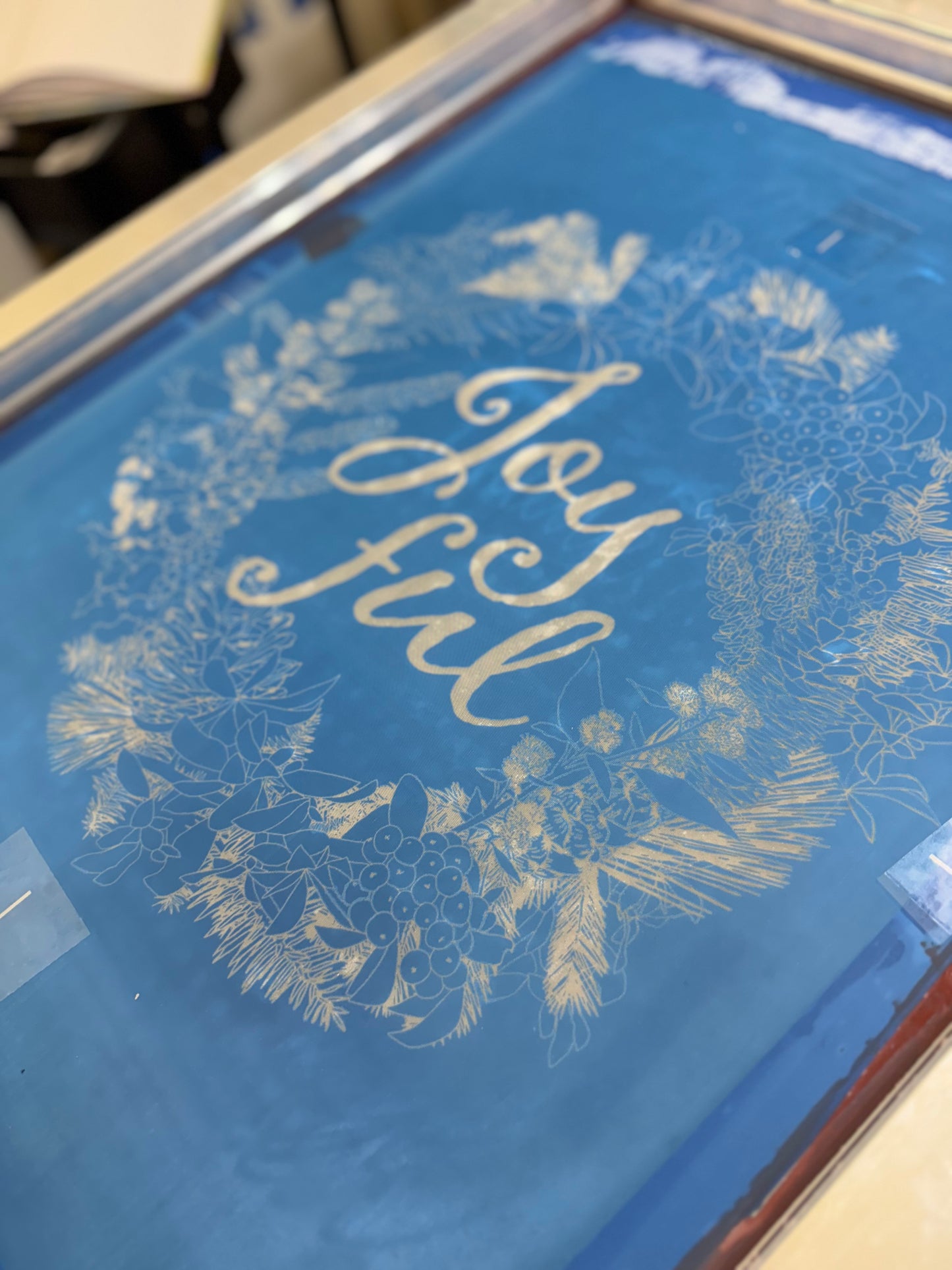 Hand-printed joyful holiday tea towel with festive botanical design